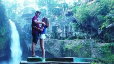 Güzel kız, erkek arkadaşıyla şelalenin yanında iyi vakit geçiriyor. Seyahat konsepti görüntüleri. 