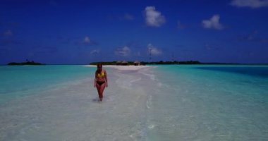 Bikini giyen, deniz tırpanı üzerinde yürüyen, bir şey düşünen bronz tenli kızın videosu. 
