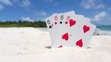 Poker kartlarının videosu, dört altılı, ve arka planda deniz plajı. 