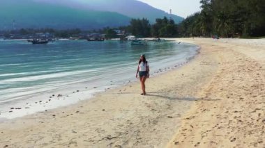 Sırt çantalı kadın turist tropik ada sahillerinde yürüyor, yaz tatili konsepti  