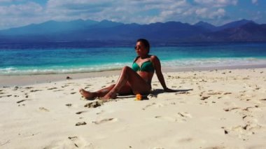 Tropik plajda güneşlenen güzel genç bir kadın.