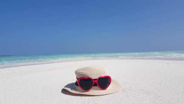 带心形太阳镜的草帽在白色沙滩上的镜头 背景为大海 — 图库视频影像