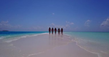 Bikinili kızların el ele tutuşup deniz tırpanı üzerinde yürüdüklerini videoya çek.