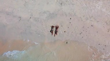 İki kızın kumlu sahilde güneşlenip güzel vakit geçirdiği en güzel manzara.