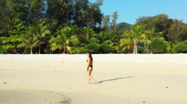 Tropik adanın kıyılarında mayo giymiş güzel genç bir kadının videosu. 