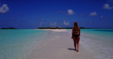 Bikini giyen, deniz tırpanı üzerinde yürüyen, bir şey düşünen bronz tenli kızın videosu. 
