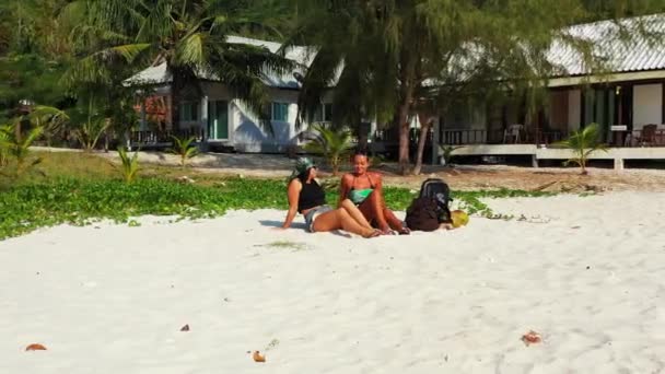 Twee Jonge Vriendinnen Zitten Aan Zandige Zeekust Met Bagage Naast — Stockvideo
