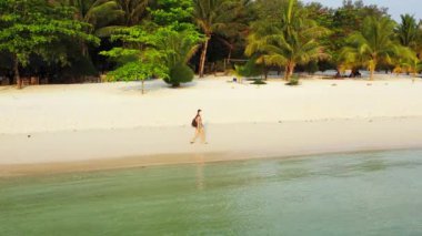 Kumsalda yürüyen maskeli bir kızın görüntüsü. 