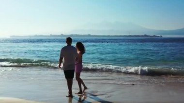 Güzel genç çift tatilin tadını çıkarıyor ve okyanusun yakınındaki güzel tropikal sahilde dinleniyor. 