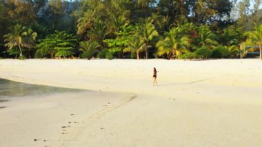 Sahilde yürüyen kulaklıklı bir kadın ve soğuk yaz gezisi konsepti. 