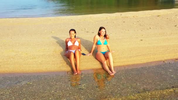 Dos Amigas Jóvenes Bikini Acuestan Costa Del Mar Tomando Sol — Vídeos de Stock