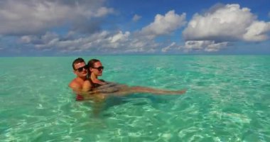 Genç adam ve kadın deniz suyunda yüzüyorlar. Tropik bir tatil köyünde dinlenen güzel bir çift.  