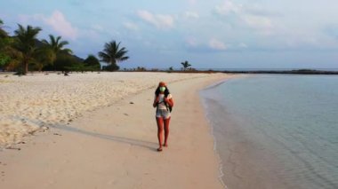 Kumsalda yürüyen maskeli bir kızın görüntüsü. 