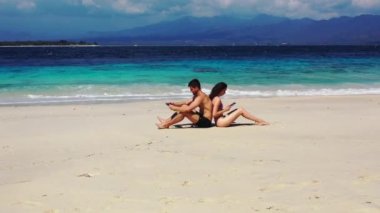  Kumsalda bir çiftin videosu. Sırt sırta oturan kadın ve adam.
