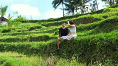 Erkek arkadaşıyla çimenlerde oturan çekici genç bir kadın, seyahat konsepti görüntüleri. 