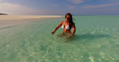 Genç bir bayan tropik sahilde güneşli bir günün tadını çıkarıyor. Maldivler plajında mutlu genç bir kadın.