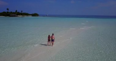 Genç bir adam ve kadın deniz suyunda yürüyorlar. Tropik bir tatil köyünde dinlenen güzel bir çift.    