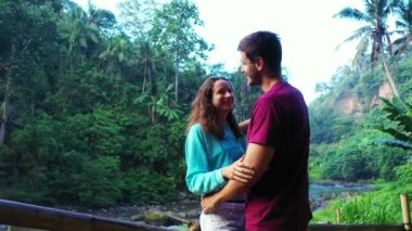 Romantik iki turist, şelale ve nehir kenarında birlikte duruyorlar.   