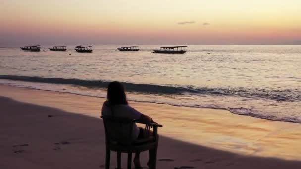 砂のビーチで椅子に座り日没の時間に — ストック動画