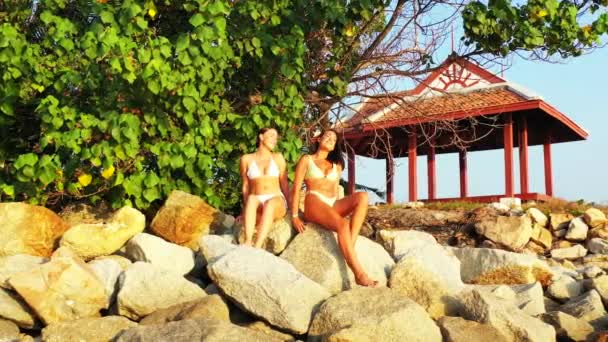 Zwei Junge Freundinnen Bikini Sitzen Auf Großen Steinen Der Küste — Stockvideo