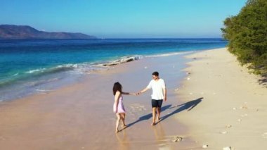 Yaz tatili konsept görüntüleri. Genç çift eğleniyor ve tropikal kumsalda yürüyor. 