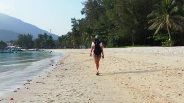 Sırt çantalı kadın turist tropik ada sahillerinde yürüyor, yaz tatili konsepti  