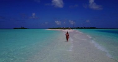 Bikini giyen, deniz tırpanı üzerinde yürüyen, bir şey düşünen bronz tenli kızın videosu. 