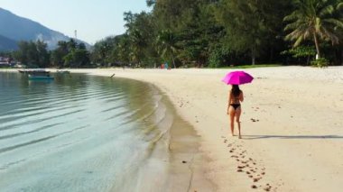 Siyah bikinili genç çekici kız kumlu sahilde yürüyor, yaz tatili konsepti  