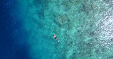 Genç adam turkuaz üzerinde yüzüyor ve şnorkelle yüzüyor. Karayip Denizi 'nin berrak suları. Güzel mercan resifleri ve dibi kayalıklarla dolu..