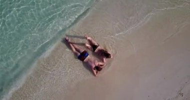 Genç bir adam ve kadın deniz kıyısında güneşleniyorlardı. Tropik bir tatil köyünde dinlenen güzel bir çift.    
