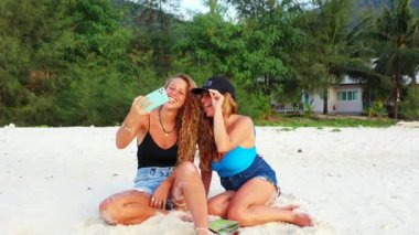 Gülümseyen çekici genç bayan arkadaşlar tropik adanın sahilinde tatilin tadını çıkarıyorlar, yaz yolculuğu konsepti görüntüleri. 