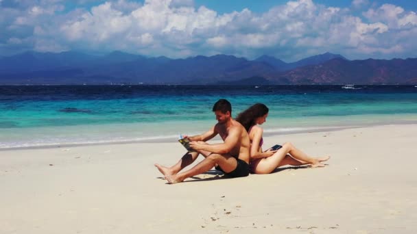 砂浜で二人のカップルと女性と男性が背を向けて座り — ストック動画
