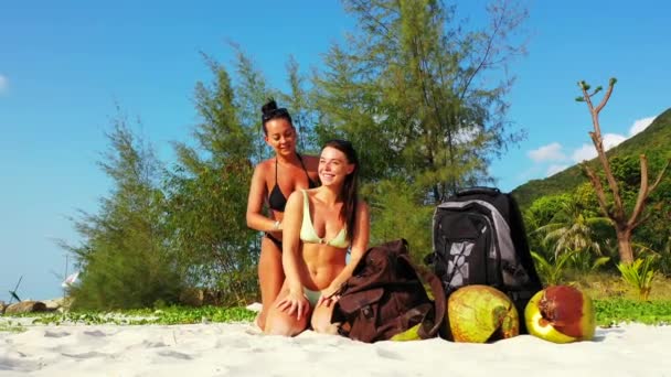砂の海の海岸 日光浴や話に座って2人の若い女の子の友人 ある女の子が女の子の友人に太陽のクリームを塗りました 熱帯リゾートにいる美しい女性 — ストック動画