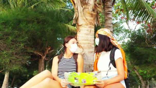 Uitzicht Meisjes Zitten Maskers Het Zandstrand Buurt Van Een Palmboom — Stockvideo