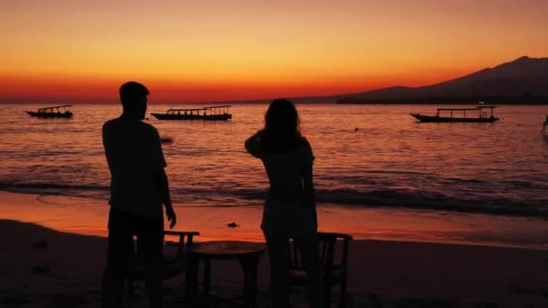 Силуэты Молодого Человека Женщины Стоящие Против Заката Над Океаном Пляжа — стоковое видео