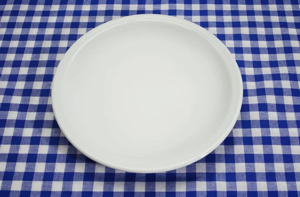 Пустая тарелка на классической клетчатой скатерти — стоковое фото
