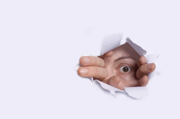 Young woman peeping through hole on paper. — Stock Photo, Image