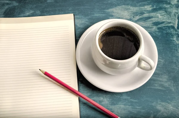 Open a blank white notebook, pencil and cup of coffee on the tab