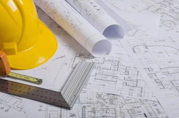 Sarı inşaat kask ve yığın proje çizimleri. 