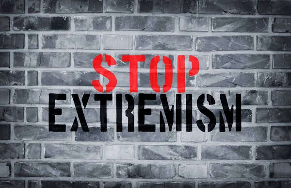 Stop Extremism stencil print on the grunge white brick wall