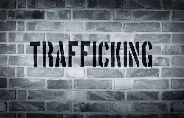 Trafficking stencil print on the grunge white brick wall — Stock Photo, Image