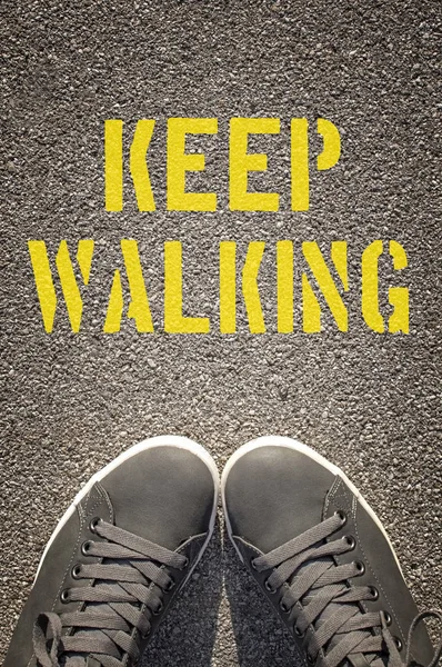Sneakers with Keep Walking written on the asphalt road — Stock Photo, Image