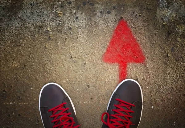 Zapatillas con flecha roja en el camino de asfalto —  Fotos de Stock