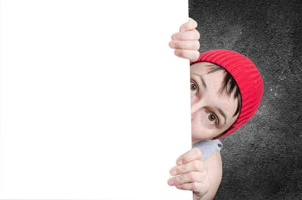 Kobieta z Red Cap zaglądając za poste papier biały billboard — Zdjęcie stockowe