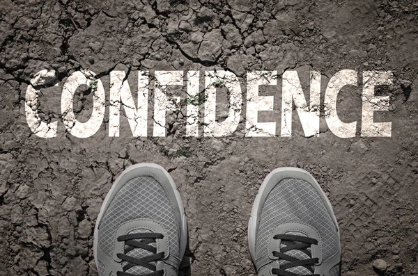 Top View of Sneakers on dry land with the text: Confidence — Stock Photo, Image