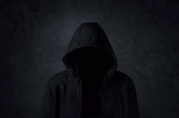 Hooded man over dark concrete background