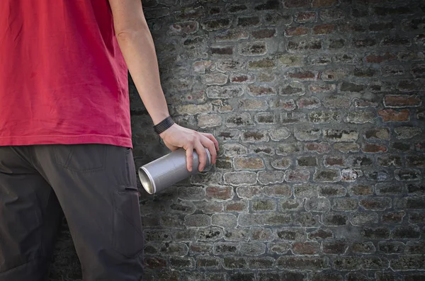 Mão segurando uma lata de spray de grafite na frente de uma parede escura — Fotografia de Stock