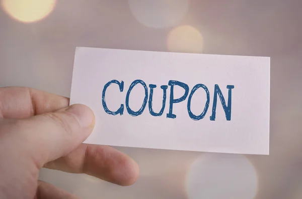 Card in hand with the word Coupon on bokeh background — Stock Photo, Image