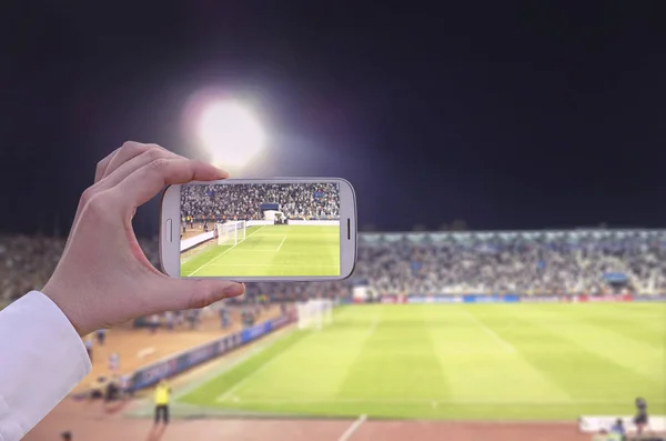 Ręka z inteligentny telefon w stadium robienia zdjęć sportowych — Zdjęcie stockowe