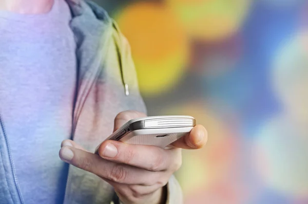 Man Texting met slimme telefoon met lichte achtergrond bokeh — Stockfoto